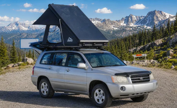 Silver SUV with a deployed rooftop tent, ideal for an RV rental outdoor adventure, overlooks stunning snow-capped mountains.. Toyota Highlander 2003