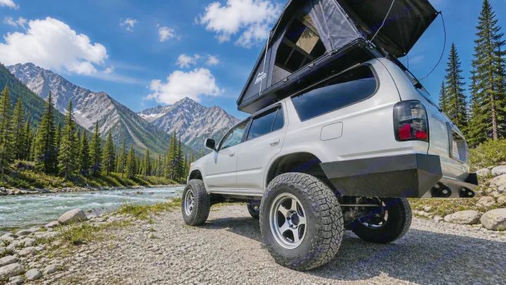 Silver off-road SUV with rooftop tent parked by a scenic mountain river. Ideal rv rental for your wilderness adventure!. Toyota 4runner 2001