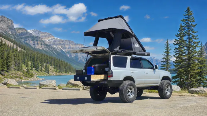 Overlanding **rv rental**: Silver 4Runner with a rooftop tent & rear storage parked by a beautiful mountain lake.. Toyota 4runner 2001