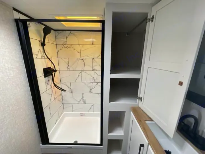 Modern RV rental bathroom showcasing a sleek shower with marble-look tiles and integrated storage cabinets.. Jayco Eagle Super Lite 2025