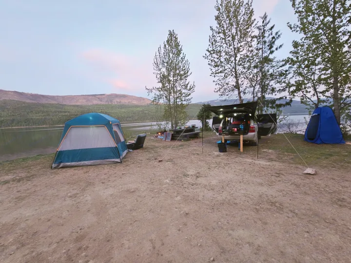 Lakeside camping at dusk: Two tents, SUV setup (like an RV rental) with canopy, plus campfire, all by the water & mountains.. Toyota Highlander 2004