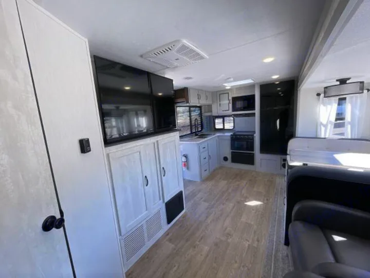 Bright rv rental interior showcasing a well-equipped kitchen, dual TVs, and light-toned cabinetry for a modern feel.. Forest River Vibe 2023