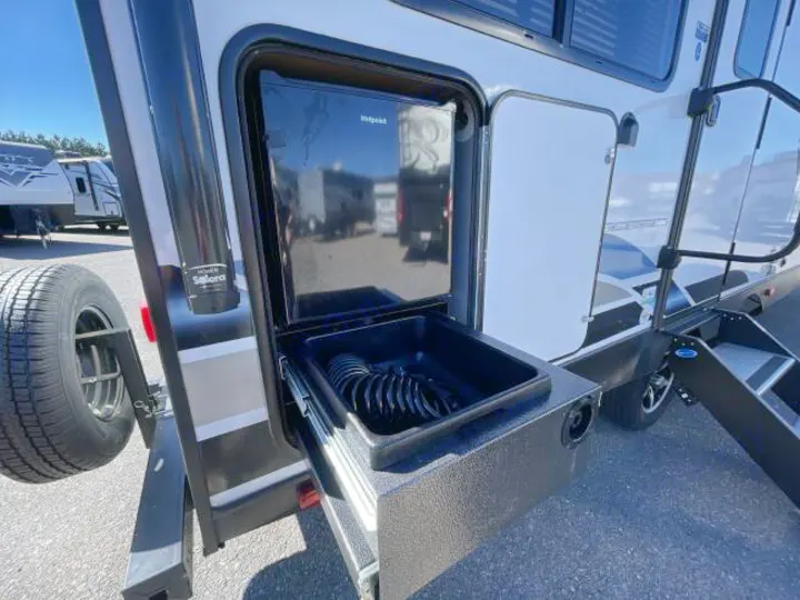 RV rental's outdoor kitchen features a Hotpoint mini-fridge, pull-out basin/shower, and spare tire, perfect for camping adventures.. Forest River Vibe 2023