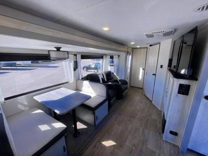 Spacious RV rental interior with a cozy dining booth, comfortable lounge, and entertainment center. Perfect for road trips!. Forest River Vibe 2023