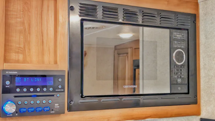 RV rental interior showing a built-in Greystone microwave oven and an iRV Technologies media receiver, fitted in a wood cabinet.. Forest River Rockwood Mini Lite 2018