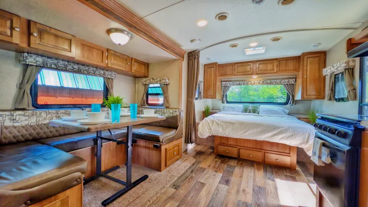 Interior of an RV rental featuring a comfortable bed, U-shaped dinette, kitchen, and ample overhead cabinets.. Forest River Rockwood Mini Lite 2018