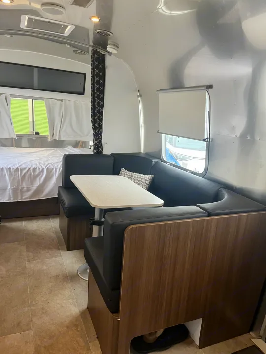 Spacious RV rental interior featuring a cozy dinette, comfortable bed, and signature aluminum walls.. Airstream Caravel 2024