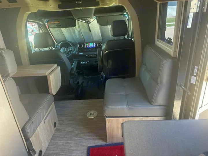 Step inside this RV rental's spacious camper van interior, featuring a dining area, comfortable seating, and front cabin view.. Winnebago EKKO 2026