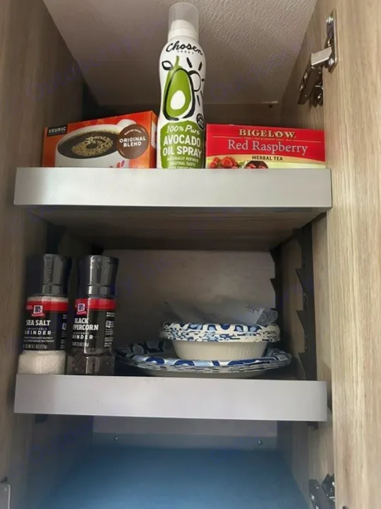 Compact RV rental kitchen cabinet with coffee pods, tea, avocado oil spray, salt, pepper, and dishes.. Winnebago EKKO 2026