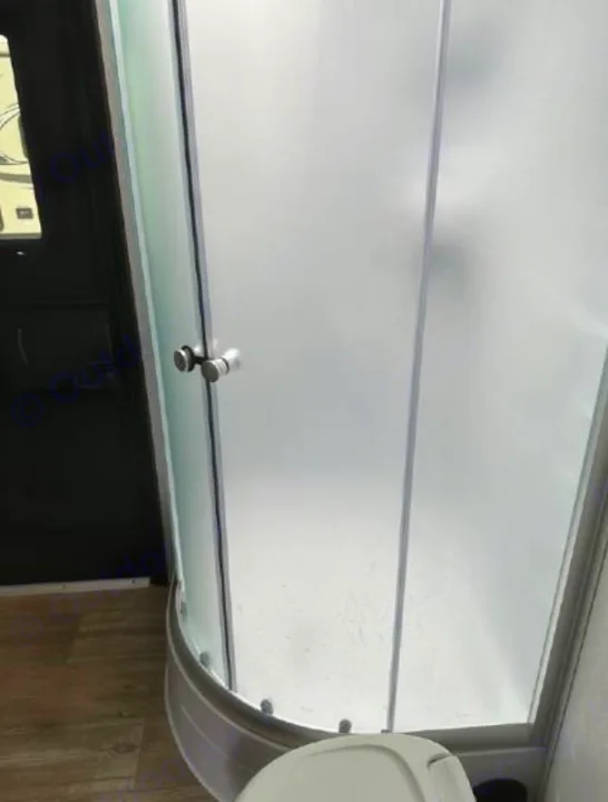 Inside an RV rental bathroom, a frosted glass corner shower and toilet offer compact convenience for your travels.. Forest River Cherokee Grey Wolf 2022