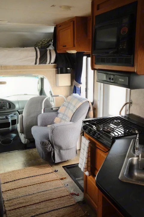 Experience comfort in this RV rental's interior, featuring a kitchen, over-cab bed, and cozy armchair.. Four Winds Majestic 2006