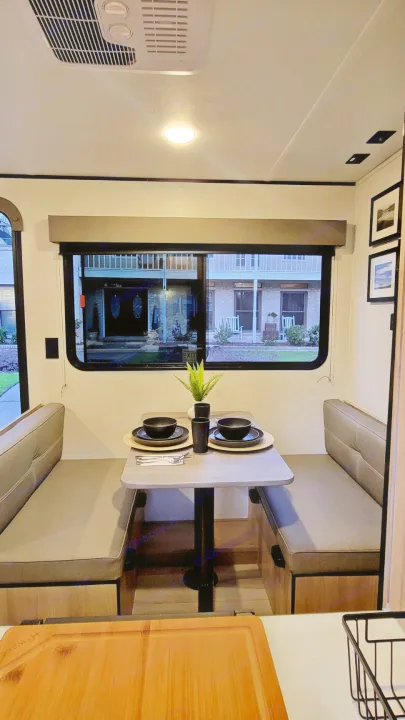 Inside a modern RV rental: a compact dinette with comfortable seating for two, elegantly set, and a window view outside.. Dutchmen Coleman 2025