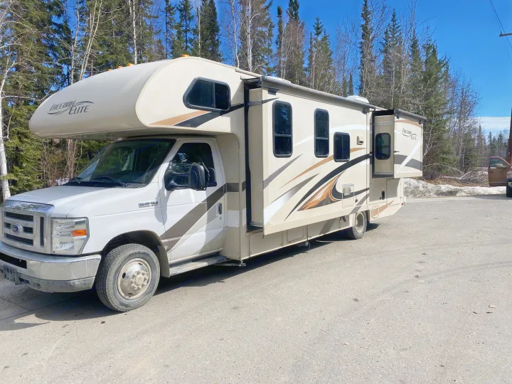 Freedom Elite Class C rv rental with slide-out, parked by trees on a sunny day. Ideal for camping & travel.. Thor Freedom Elite 2016
