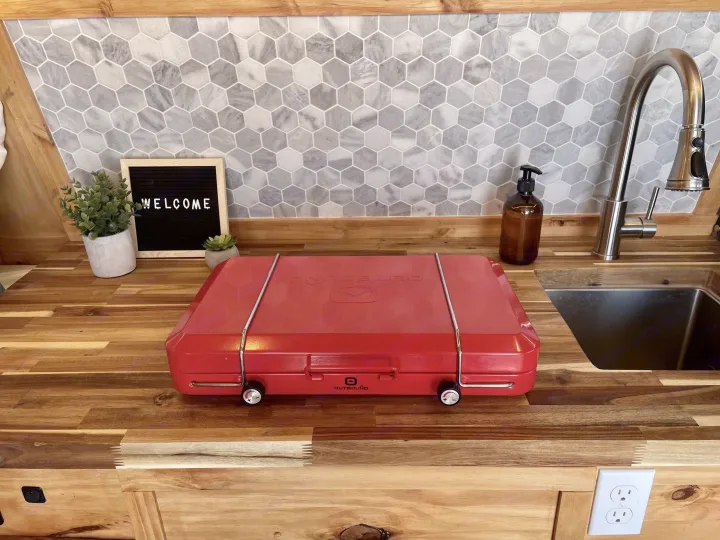 This cozy RV rental kitchen features a red portable stove, wooden counters, and a modern hexagonal backsplash.. Gmc Savanna 2500 2016
