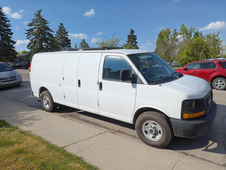 This white GMC cargo van, often used for RV rental conversions, is parked on a sunny street with trees in the background.. Gmc Savanna 2500 EXT 2016