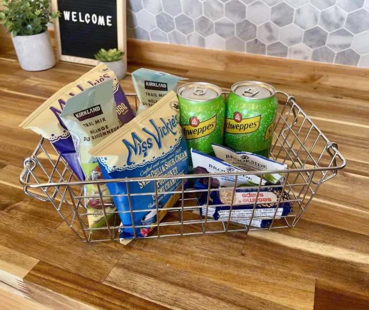 Welcome basket in an RV rental kitchen, featuring chips, trail mix, chocolate, and Schweppes ginger ale on a wooden counter.. Gmc Savanna 2500 2016