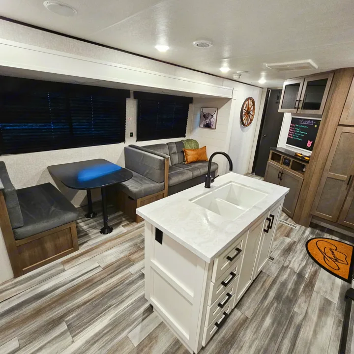 Inside a stylish RV rental: modern kitchen island, comfortable dinette seating, and chic wood-plank flooring.. Jayco SLX 2025