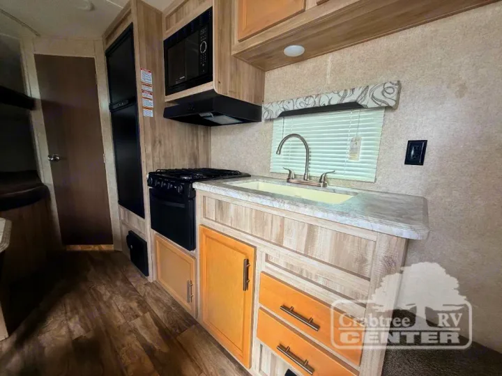 Inside an RV rental: a compact kitchen with stove, microwave, sink, refrigerator, and light wood cabinets.. Coachmen Other 2020