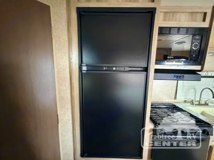 RV rental kitchen area features a tall black refrigerator, microwave, stovetop, and sink, showing convenient appliances.. Coachmen Other 2020