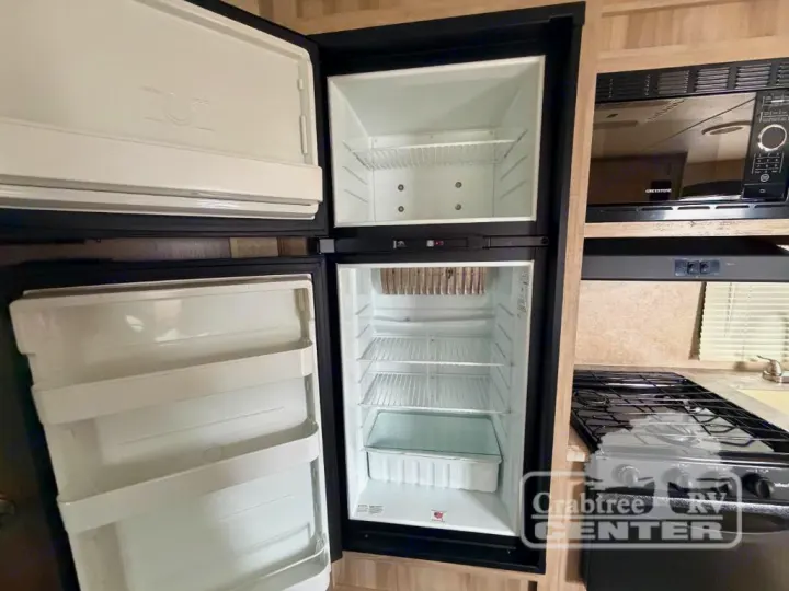 An RV rental kitchen with an open two-door fridge/freezer, microwave, and stovetop, equipped for your travels.. Coachmen Other 2020