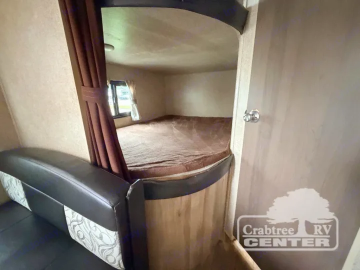 Inside an RV rental: a cozy bunk bed area with a brown curtain, sofa seating, and a wooden door on the right.. Coachmen Other 2020