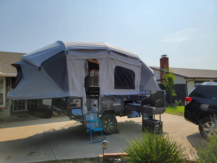 Opus Off-Road pop-up camper trailer with outdoor kitchen, set up in a driveway. An ideal rv rental for adventure!. Air Opus OP4 2021