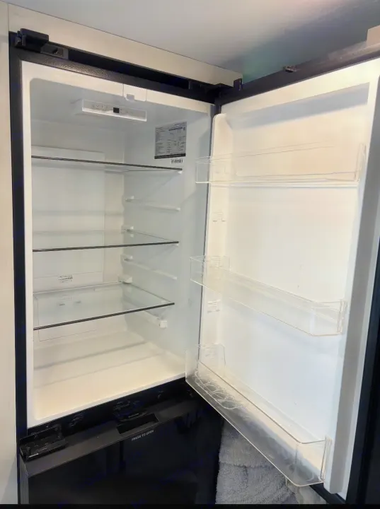 Clean, empty RV rental refrigerator interior with glass shelves and door bins, ready for your trip essentials.. Puma Palomino 2024