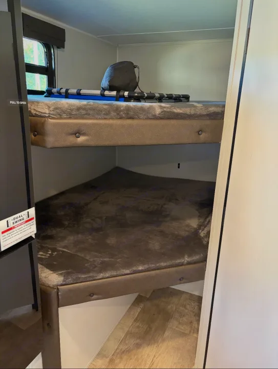 Cozy bunk beds in an RV rental, featuring soft gray blankets on both. The top bunk has a bag and rolled items, ready for travel.. Puma Palomino 2024