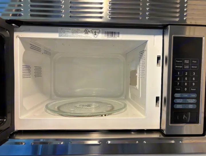 Compact, clean microwave in an RV rental kitchen, ready for use. It has a glass turntable and silver control panel.. Puma Palomino 2024