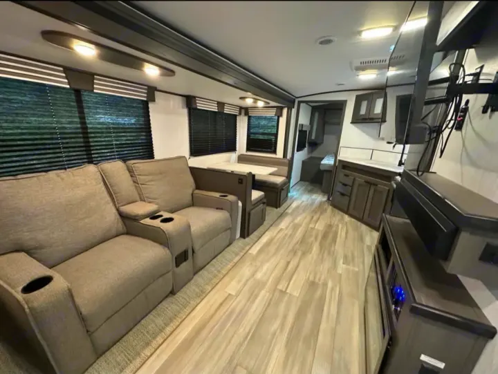 Spacious rv rental living area with recliners, dining booth, kitchen counter, and entertainment unit for comfort.. Cruiser RV MPG 2022