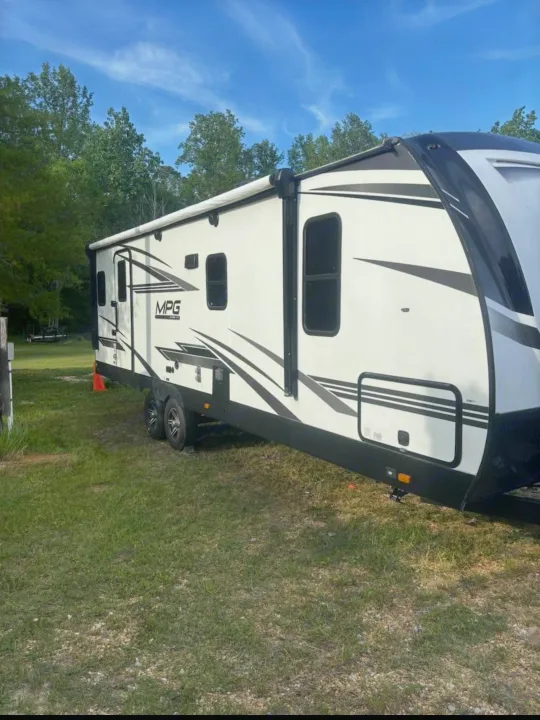 Get ready for adventure! This modern white MPG rv rental is parked in a grassy spot, ready for your outdoor escape.. Cruiser RV MPG 2022