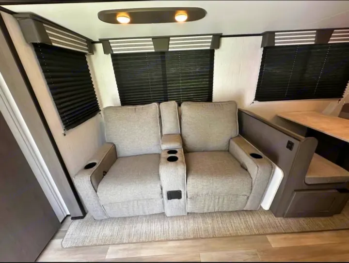 Cozy RV rental interior with light grey recliners, cup holders, and a dinette booth for comfortable seating in your camper.. Cruiser RV MPG 2022