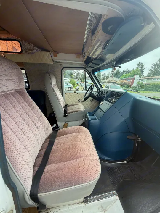 Interior of an RV rental: front seats, blue dashboard, and view from the cab. Ready for travel.. Chevrolet G20 1987