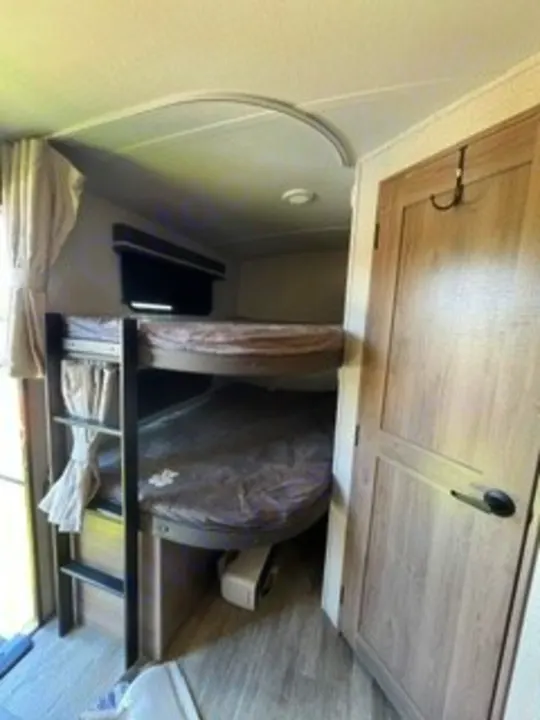 RV rental with clever bunk beds; the lower bunk curves for a compact interior sleeping area next to a door.. Grand Design Imagine 2022
