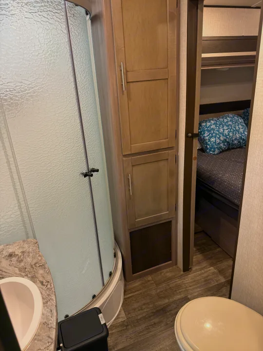 RV rental: Compact bathroom with textured glass shower, sink, toilet, and an adjacent cozy bedroom.. Crossroads RV Sunset Trail Super Lite 2022