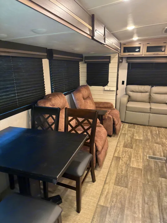 RV rental: Interior view showing a dining table, plush recliners, and a sofa, with modern flooring & blinds.. Crossroads RV Sunset Trail Super Lite 2022