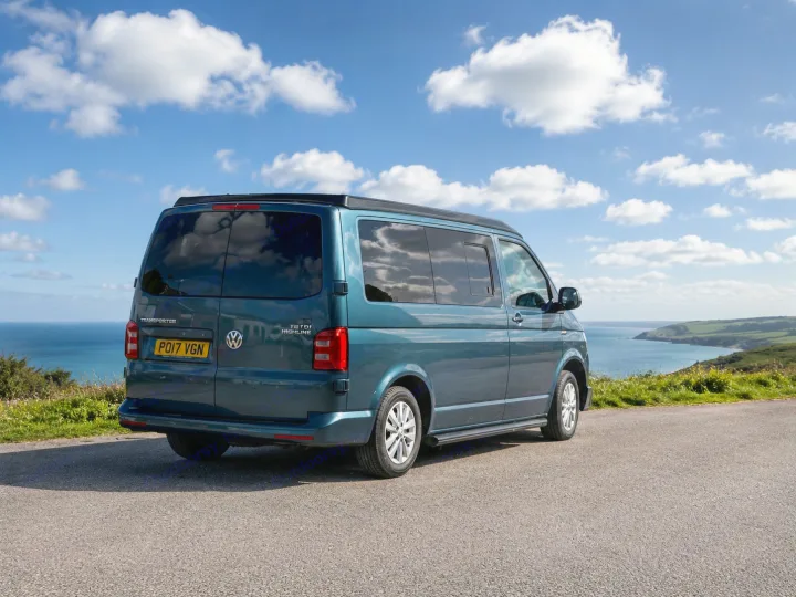 Blue VW camper van, ideal for rv rental, parked on a scenic coastal road overlooking the ocean under a partly cloudy sky.. Volkswagen Other 2017