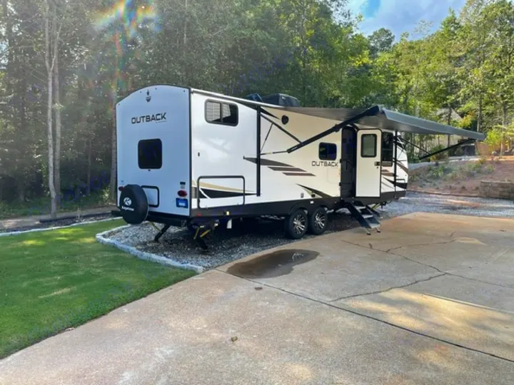 This white Outback RV rental is parked with its awning extended in a natural, wooded setting, ready for your next adventure.. Keystone RV Bullet Premier Ultra Lite 2022