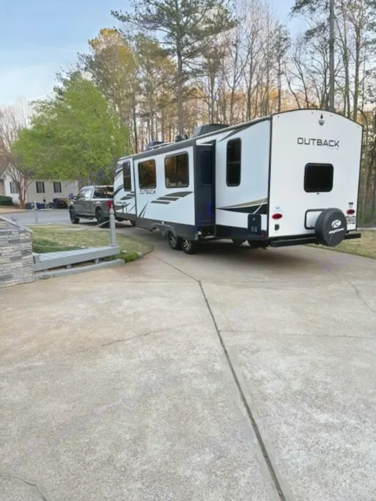 Large Outback rv rental travel trailer, hitched to a truck on a driveway, ready for your next adventure or outdoor escape.. Keystone RV Bullet Premier Ultra Lite 2022