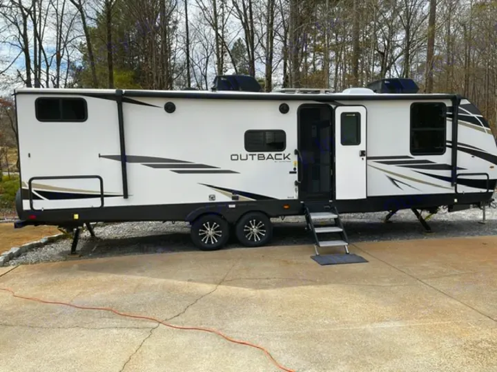 White travel trailer RV rental, "Outback" brand, parked on concrete with steps down. Perfect for camping trips.. Keystone RV Bullet Premier Ultra Lite 2022
