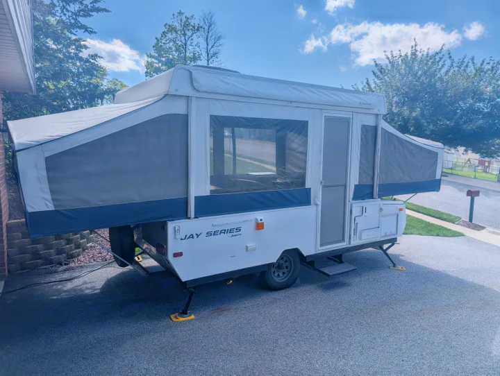 White Jayco Jay Series pop-up camper, fully extended & parked on a driveway. An ideal rv rental for your travels.. Jayco Select 2006