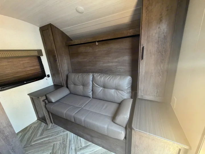 Inviting rv rental interior with a gray sofa, storage cabinets, and a clever murphy bed system for guests.. Forest River Salem Select 2021