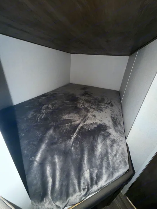 Inside a compact **RV rental**, a comfy dark grey bunk bed provides a snug sleeping space, with light walls and a dark ceiling.. Forest River Salem Select 2021