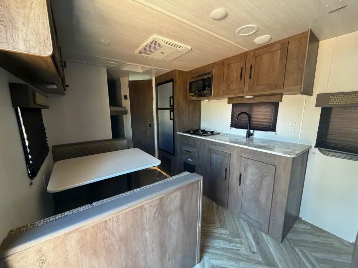 Cozy RV rental interior: modern kitchen with microwave, stove, and fridge, plus a comfortable dinette. Ready for travel!. Forest River Salem Select 2021