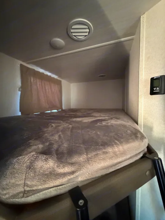 Cozy RV rental bunk bed with a soft blanket, ceiling vent, and digital climate control for a comfortable sleeping area.. Forest River Salem Select 2021