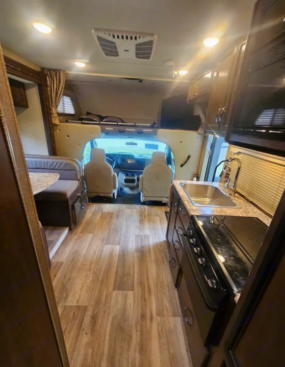 Spacious RV rental interior with dinette, kitchen, driver's area, and overhead bunk. Perfect for road trips.. Thor Four Winds 2018