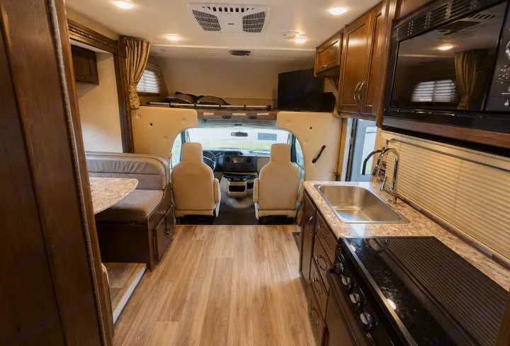 Spacious RV rental interior with a modern kitchen, comfortable dinette, driver's area, and overhead bunk. Ideal for travel.. Thor Four Winds 2018