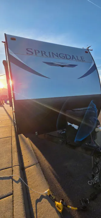 Springdale by Keystone travel trailer, perfect for an rv rental, parked on a street during golden hour, hinting at adventure.. Keystone RV Springdale 2021
