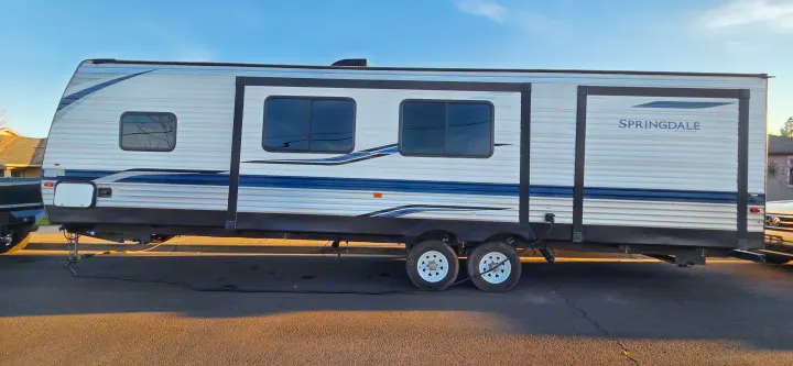 This white Keystone Springdale travel trailer RV rental, featuring blue stripes & multiple windows, is ready for adventure.. Keystone RV Springdale 2021