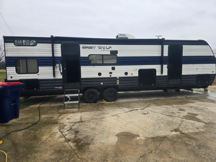 A Grey Wolf Limited travel trailer, ideal for an rv rental, is parked on concrete with its doors open on a cloudy day.. Forest River Cherokee Grey Wolf 2024